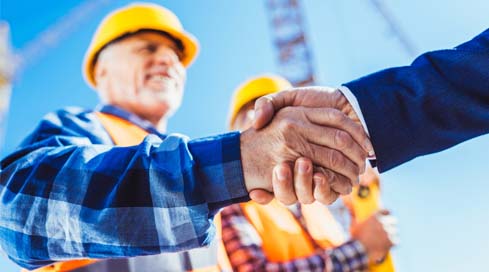 Construction finance manager shakes hands with a business partner on the job site