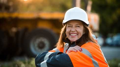 Female project manager smiling after reviewing her construction inventory on a construction site - outdoor at sunset