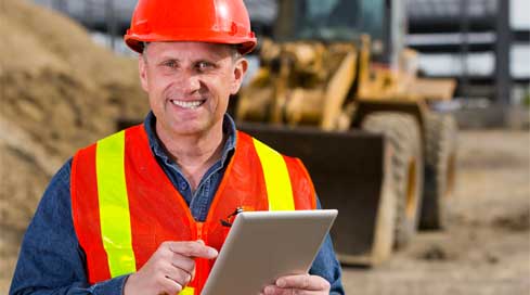 Project manager using tablet to verify construction timesheets on a job site